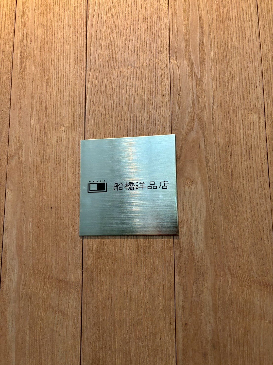 木の扉に付いた『船橋洋品店』の金属の表札