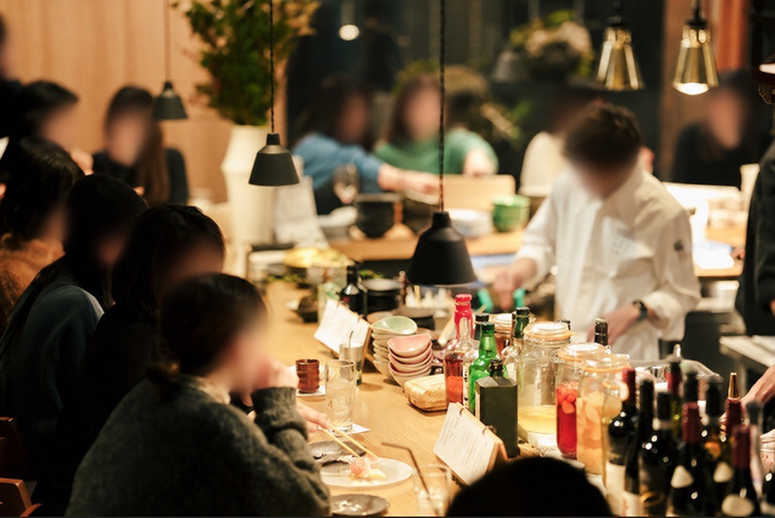 オープンキッチンを囲むカウンターに客が並び、料理人が調理している