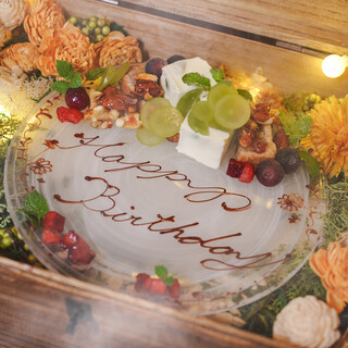 「Happy Birthday」と書かれたガラスの皿に、季節の果物とチーズ、ナッツの甘味